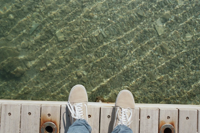 a person is standing on a boardwalk in front of the water
