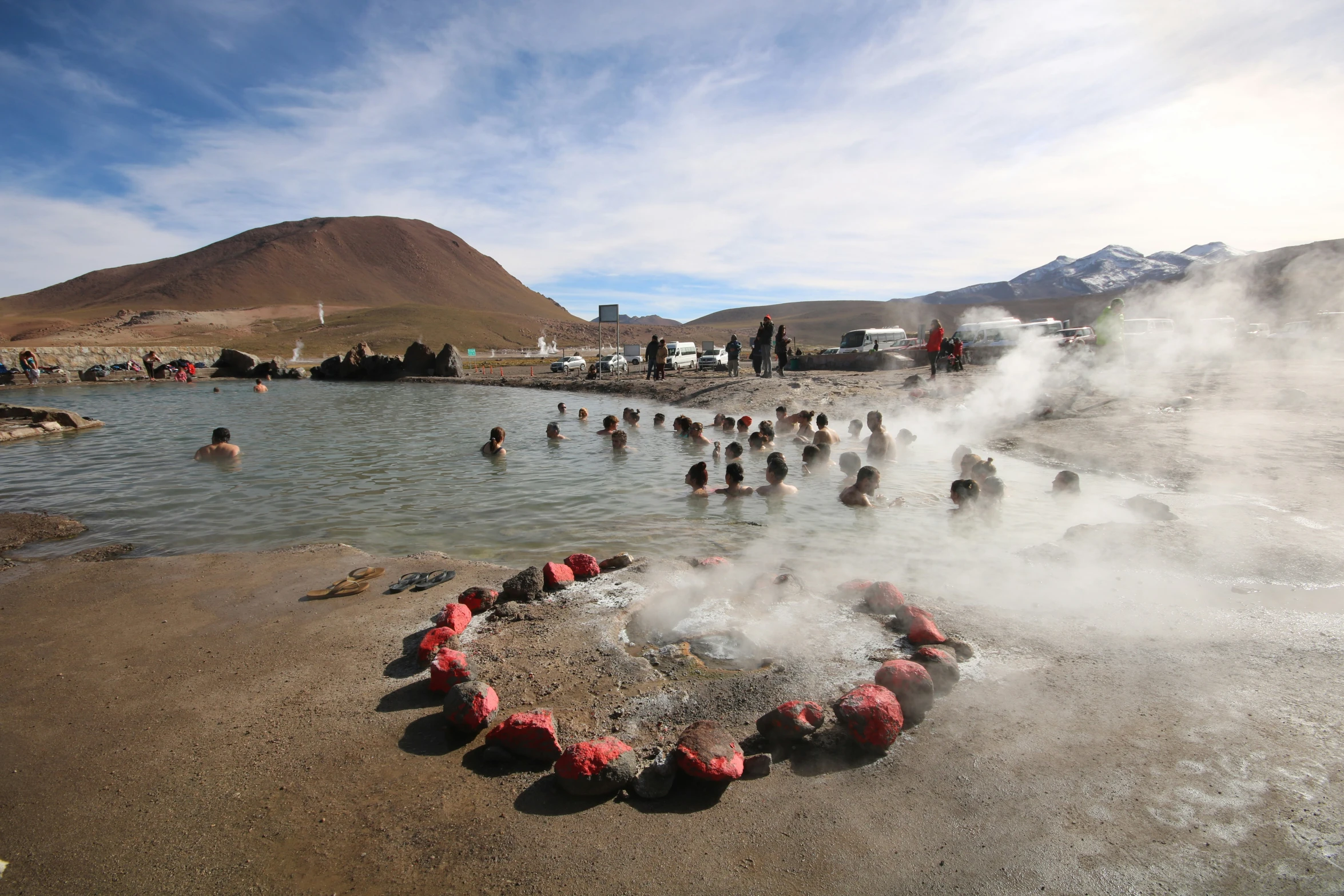 a heart of people swimming in a lake near a hill