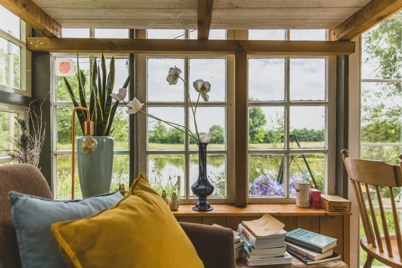 a home sitting near a lake with windows and books on a couch