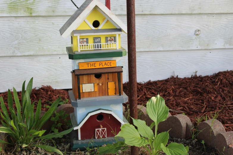 a house shaped birdhouse with a bird perched on top