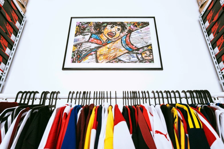 clothes hang in racks in the closet under a framed artwork