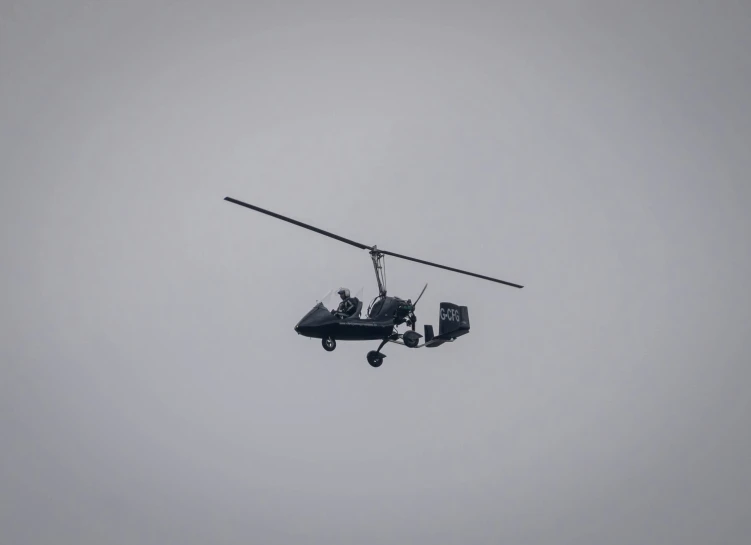 a helicopter flies in the air while two soldiers sit inside it