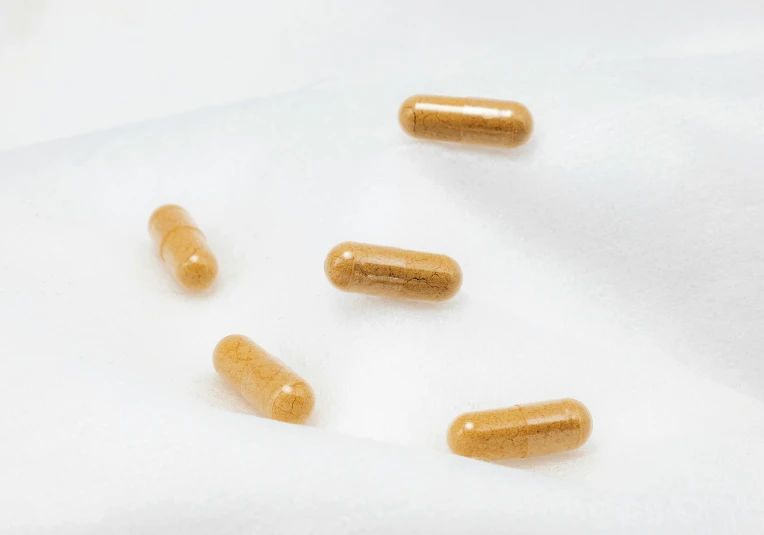 several yellow pills laying on top of a white cloth