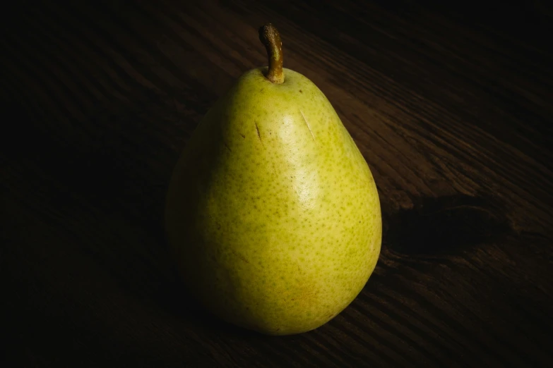 there is a pear on a table with dark background