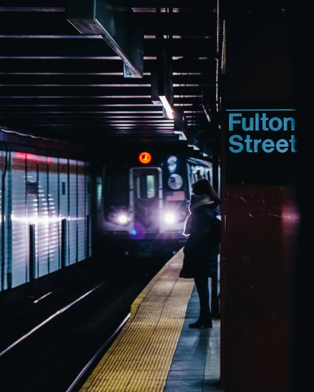 a train pulling into a train station with the words fulton street written on it