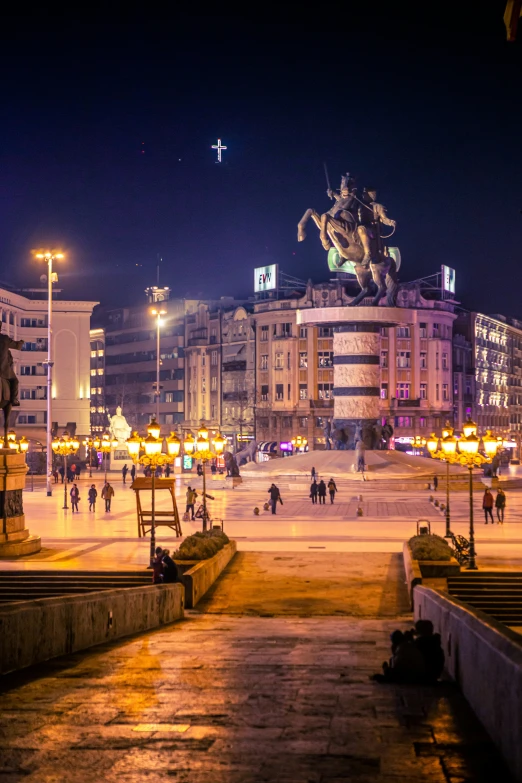 an intersection with people and statues at night