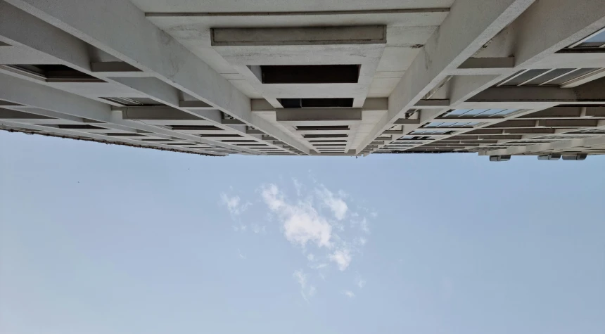 the bottom of an industrial bridge with a stop sign below