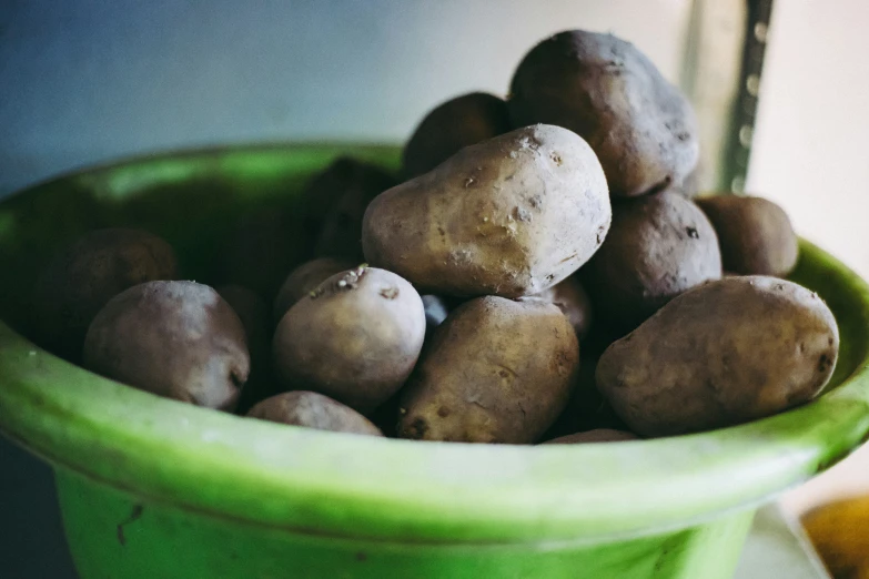 potatoes in green bowl, next to orange slice