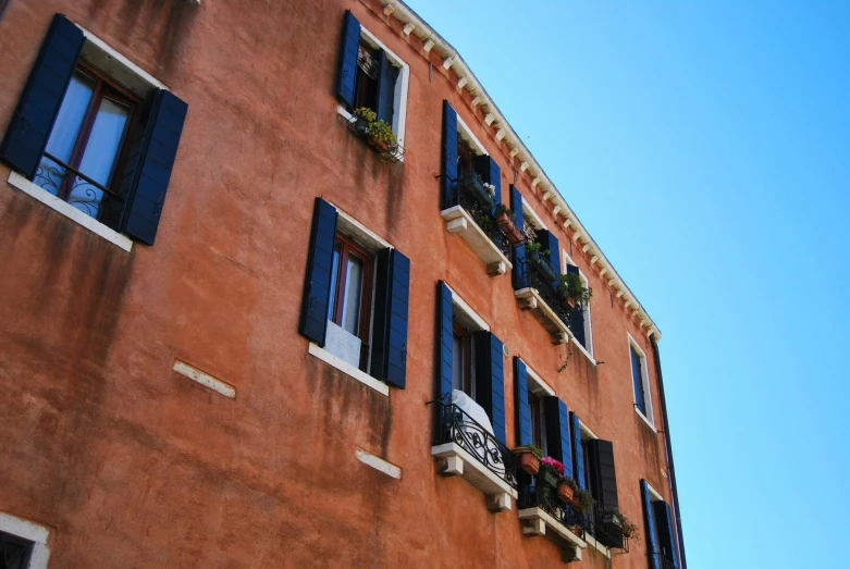 tall orange brick building with black shutters and blue sky in background