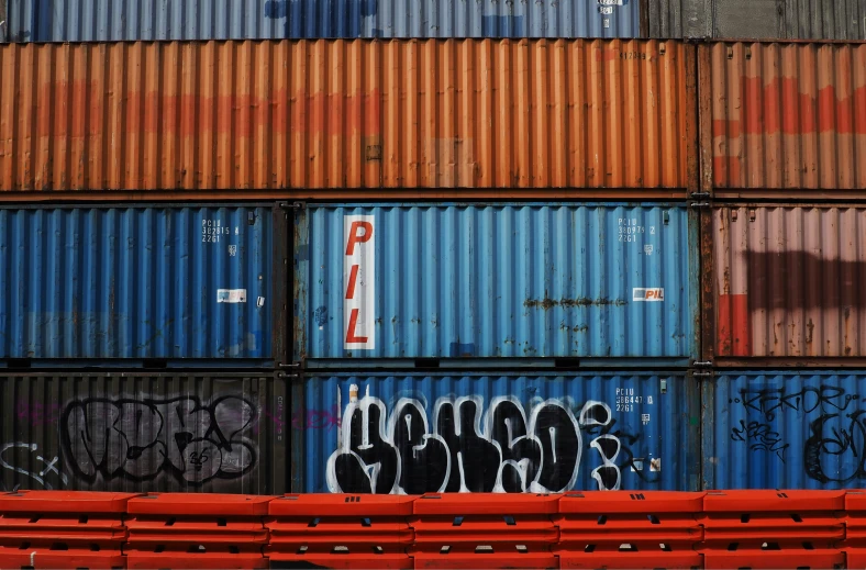 several red seats are positioned against an array of shipping containers