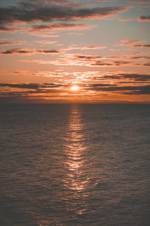 an orange sky on the water is reflected by sunlight