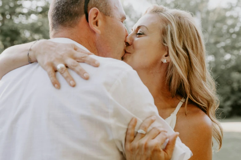 a beautiful blond woman kissing a man as he hugs her