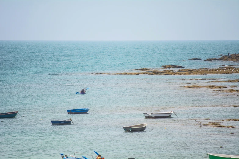 there are several boats in the water near some rocks