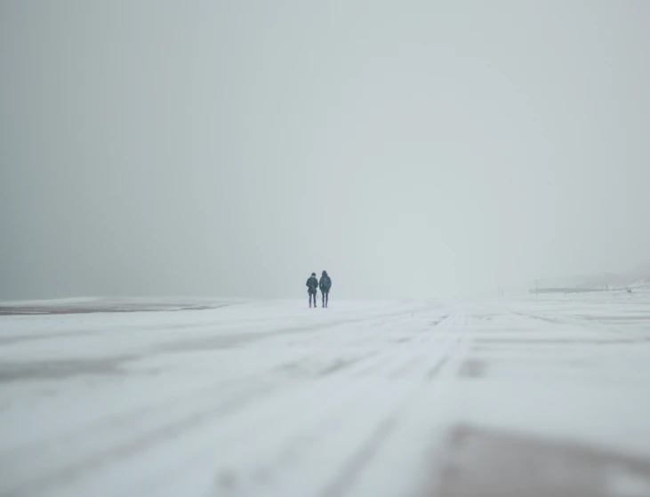 a man and woman walking down a snowy road