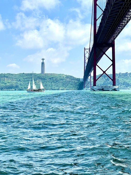 the ocean is very blue and calm under a bridge