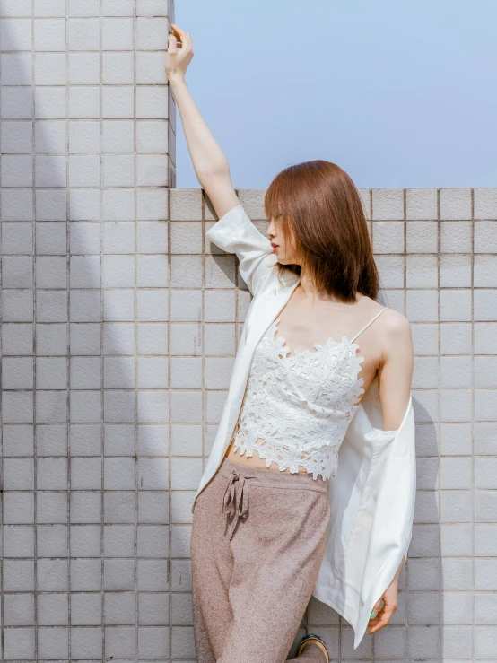 a woman leaning against a brick wall wearing a skirt and white blouse
