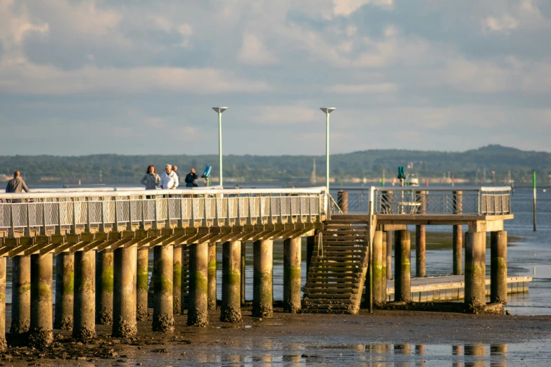 a man and two women stand on a pier and look out over the water