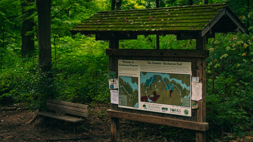 a bench with a sign beside it in front of trees