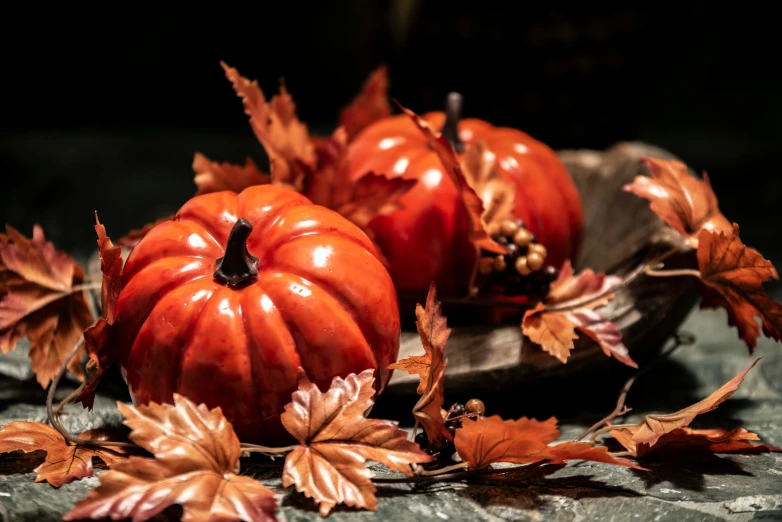 a bunch of pumpkins with fallen leaves on the ground