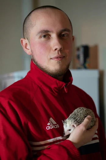 a young man holding an adorable hedgehog in his arms