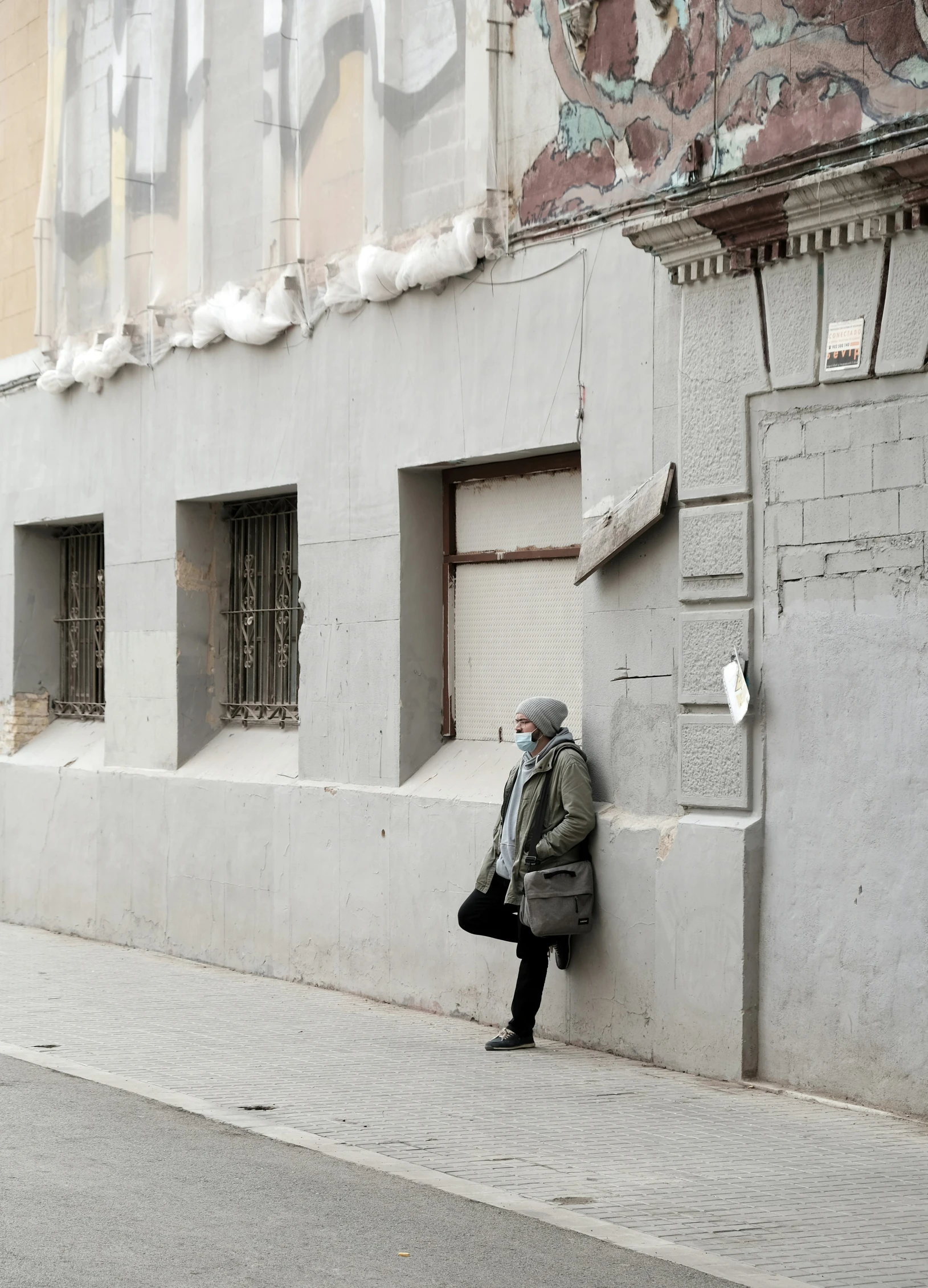 a person on the side of a road leaning against a building