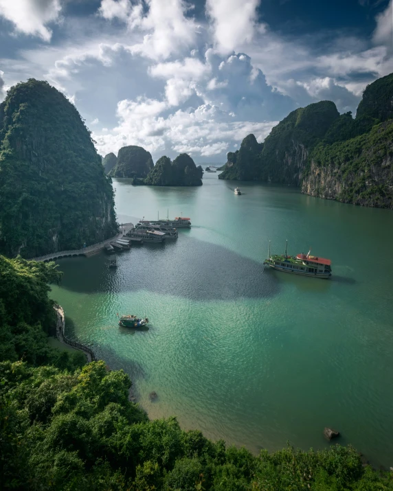 boats are sailing on a green river near many large mountains