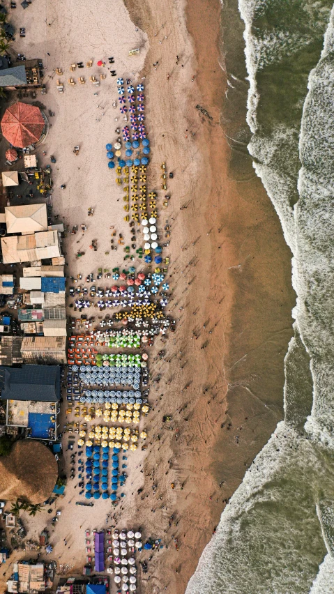 this is an aerial view of a beach and its various colored chairs