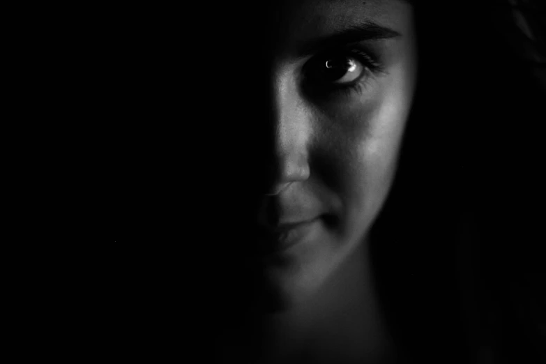 a black and white po of a woman's face with dark background