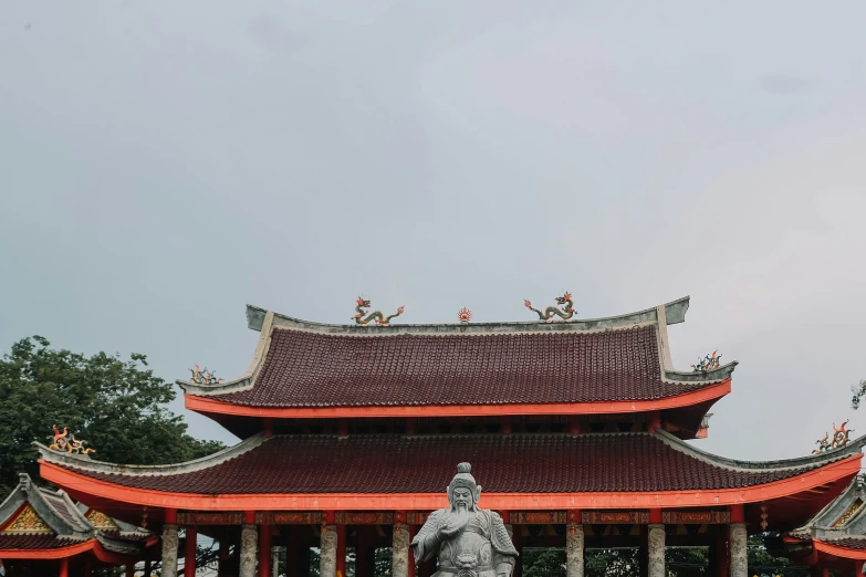 a statue stands in front of a pagoda