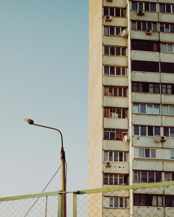 a city skyline shows a tall white building and a fence