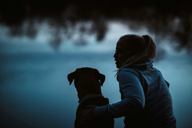 a woman holds her dog's face up to the water