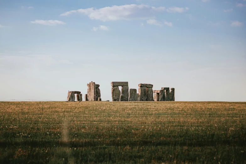 a group of stonehenge on the ground of a field