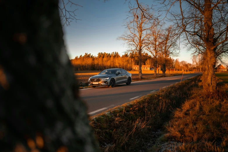 a car sits parked in the street near some grass