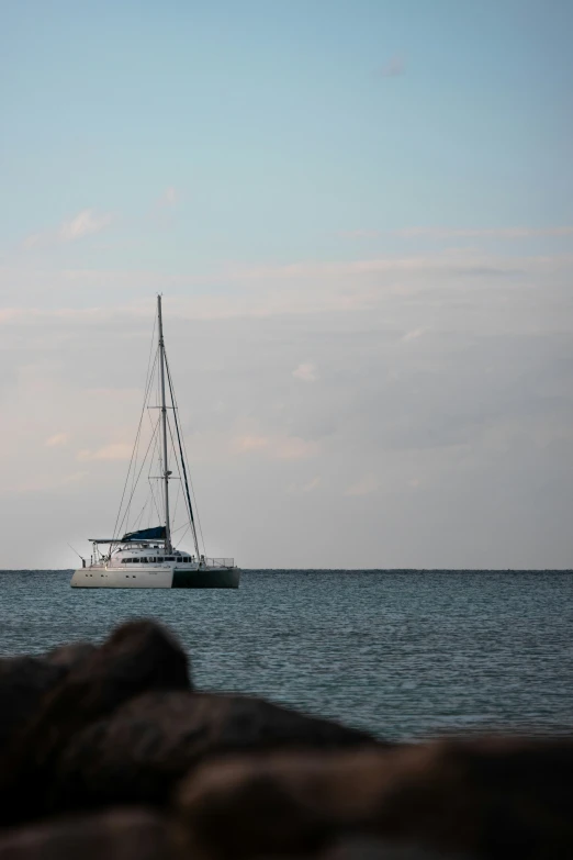 a white sail boat floating next to the shore