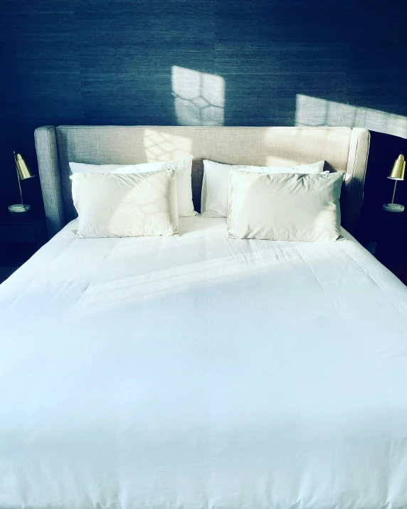 there is a bed with white linens and two lamps