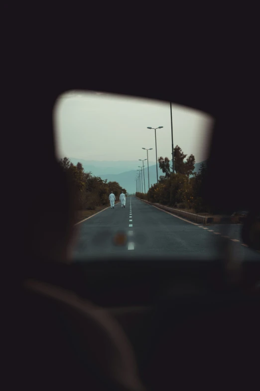 a s of a car's rear view mirror showing an empty street
