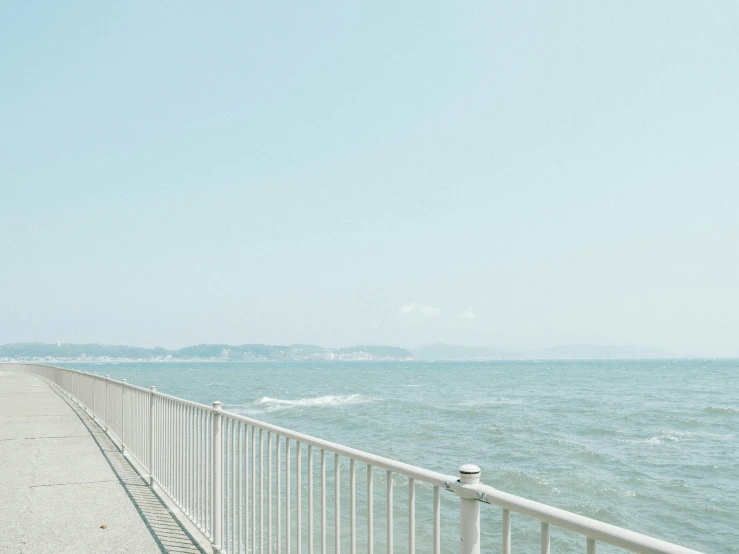 the ocean and walkway is lined with wire railings