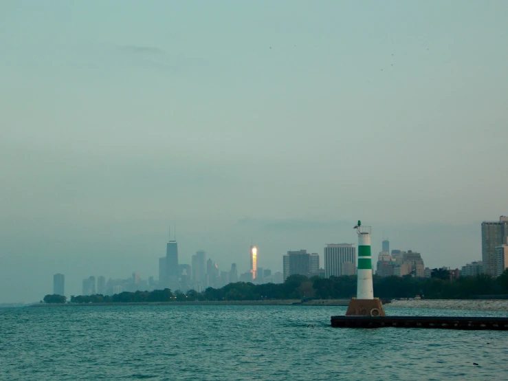 a green and white light house sitting on the edge of the ocean