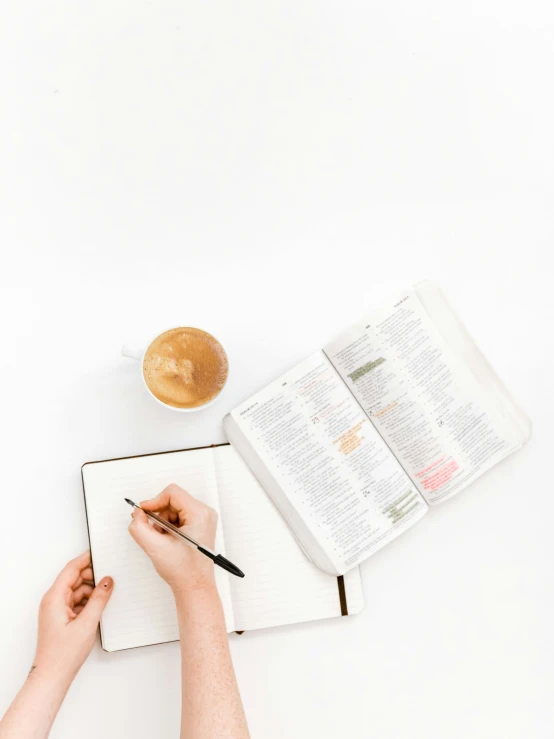 the woman is holding a pen while writing in her notebook