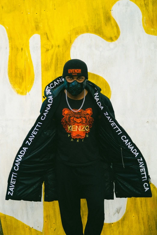 a man with a t - shirt on and a helmet standing against a yellow and white background