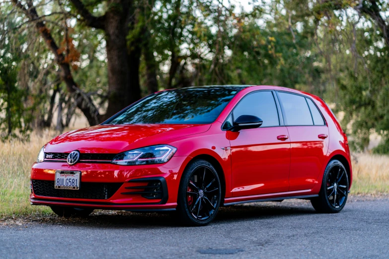 a red vw golf gti clubs sedan parked in front of some trees
