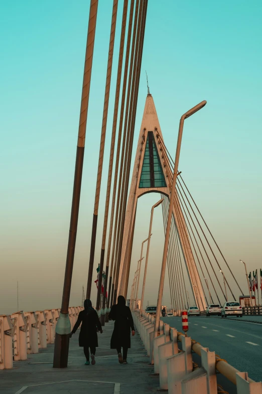 people are walking across a pedestrian bridge