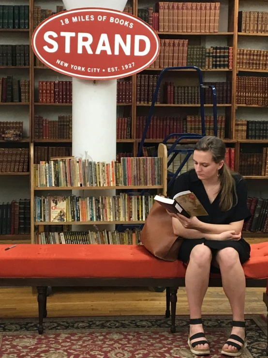 a woman is sitting down reading on the bench