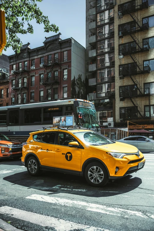 a bright yellow vehicle at an intersection with another car and bus