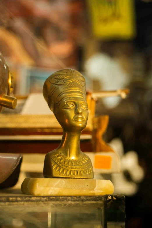 a gold figure sitting on a table next to a vase