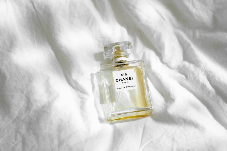 a clear perfume bottle sitting on top of a white cloth