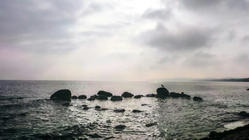 several rocks in the ocean during a cloudy day