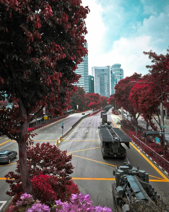 an army tank riding down a road surrounded by red flowers