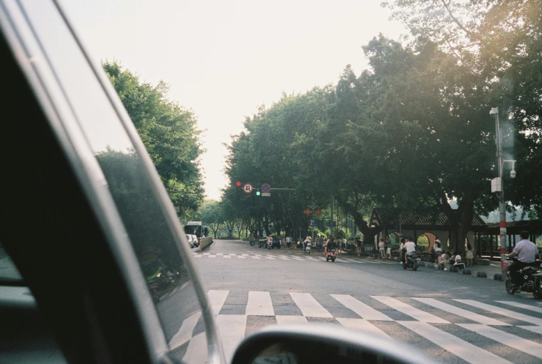 a car stopped at an intersection while people are walking down the street