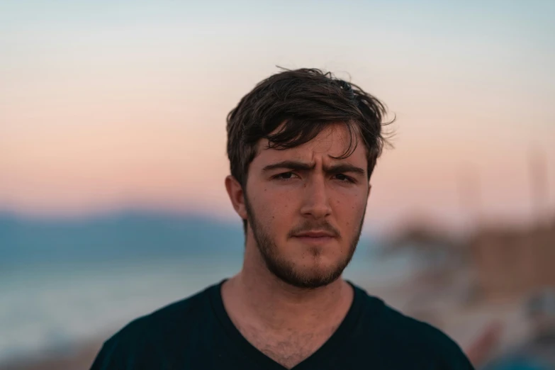 a man stands near the ocean looking sad